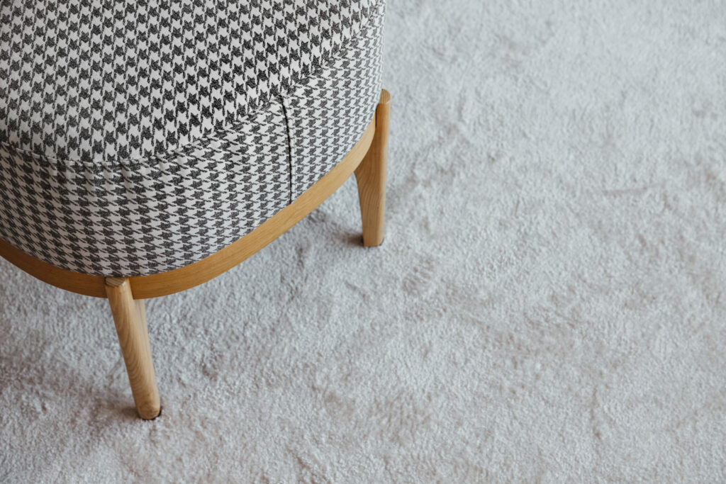 Checkered bench with wooden legs on a fluffy carpet, top view with free space