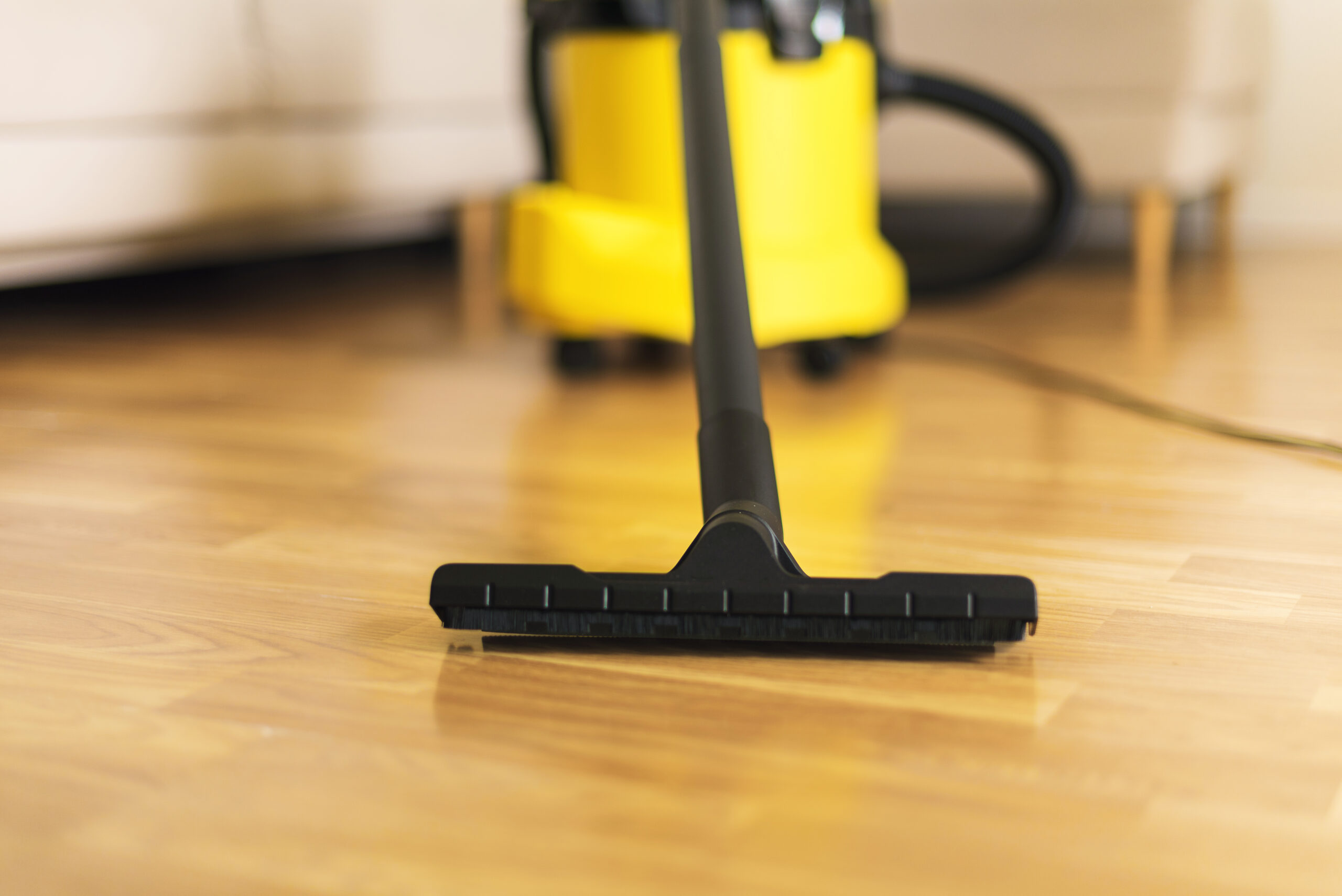 Woman in protective gloves cleaning the living room with yellow vacuum cleaner. Copy space. Clean concept