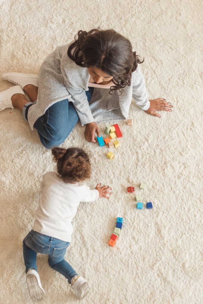 mother and little daughter playing with cubes together at home