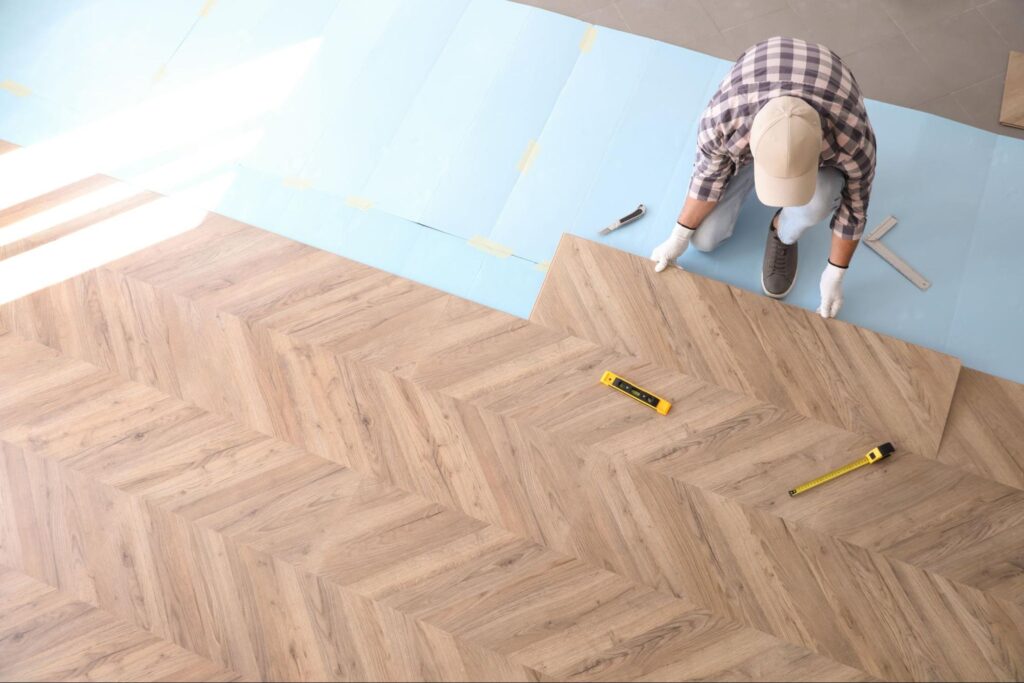 worker-installing-laminated-wooden-floor-indoors-above-view